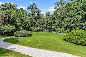 A green park with a gravel path and a fence.