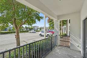 A balcony with a black railing and a tree in the foreground.