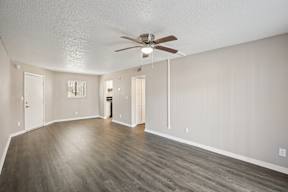 A spacious room with a ceiling fan and hardwood flooring.