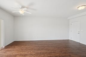 A room with a ceiling fan and brown flooring.