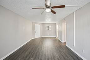 A room with a ceiling fan and wooden flooring.