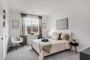 A bedroom with a large bed and a chair.