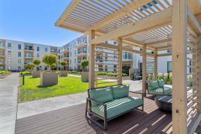 a patio with green chairs and a wooden pergola