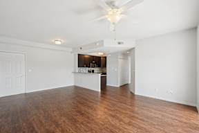 A spacious room with a ceiling fan and wooden flooring.