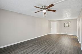 A room with a ceiling fan and wooden flooring.