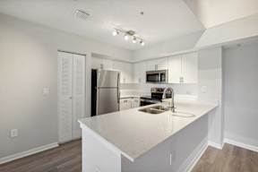 A kitchen with white cabinets and a stainless steel refrigerator.