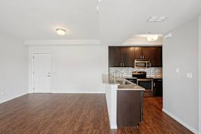 A kitchen with a white island and dark wood cabinets.