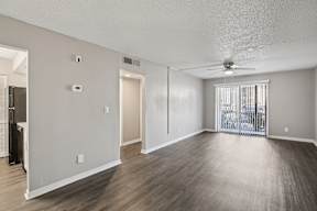 A spacious room with a ceiling fan and sliding glass doors.
