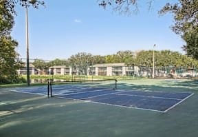 A tennis court surrounded by a fence and trees.