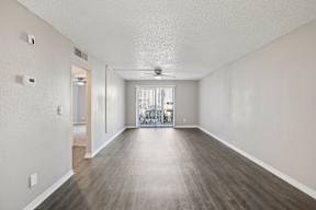A spacious room with wooden flooring and a ceiling fan.