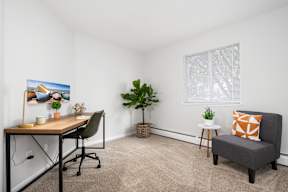 A room with a desk, chair, and potted plant.