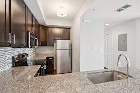 A kitchen with a granite counter top and stainless steel appliances.