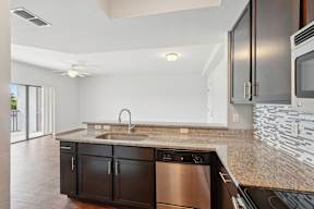 A modern kitchen with a stainless steel dishwasher and black cabinets.