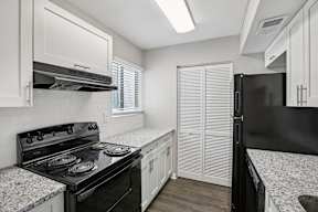 A black stove in a kitchen with white cabinets.