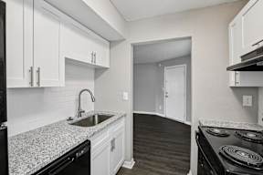 A kitchen with white cabinets and a black stove top oven.