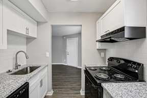 A kitchen with a black stove top oven and white cabinets.