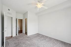 A room with a ceiling fan and carpeted floor.