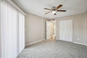 A room with a ceiling fan and carpeted floor.