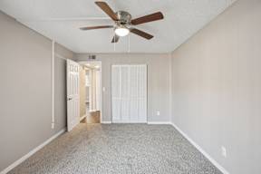 A room with a ceiling fan and carpeted floor.