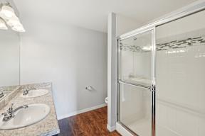 A bathroom with a sink, mirror, and shower.