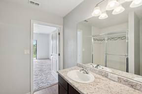 A bathroom with a sink, mirror, and lighting fixture.