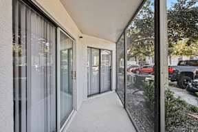 A balcony with glass doors and a view of a parking lot.