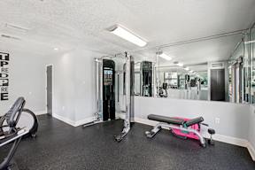 A gym with a pink bench and a mirrored wall.