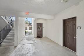 A hallway with a brown door and a red exit sign above it.