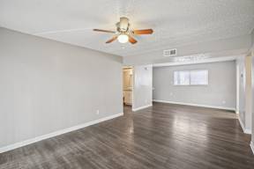 A room with a ceiling fan and wooden flooring.