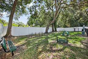 A park with a white fence and a green bench.