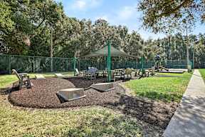 A playground with a green canopy and a fence.