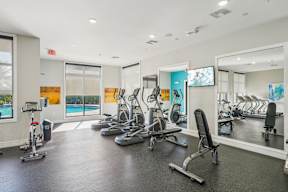 A gym with a variety of equipment including treadmills, stationary bikes, and weight machines.