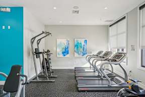A gym with treadmills, a stationary bike, and a painting on the wall.