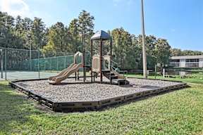 A playground with a slide and a wooden swing set.
