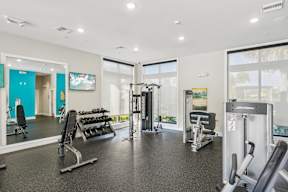 A gym with a variety of equipment including weights and cardio machines.