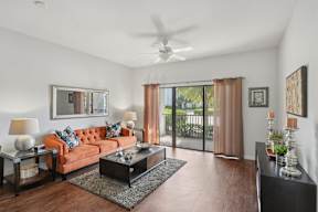 A living room with a brown sofa, a coffee table, and a ceiling fan.