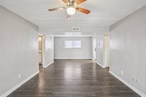 A room with a ceiling fan and wooden flooring.