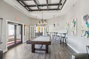 A room with a pool table and bar stools.