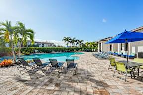 A pool surrounded by chairs and umbrellas.