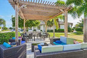 A wooden pergola over a patio with wicker furniture.