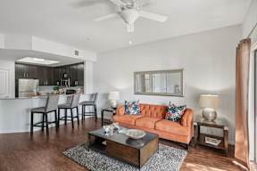 A living room with a brown sofa, a coffee table, and a ceiling fan.