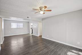 A room with a ceiling fan and hardwood floors.
