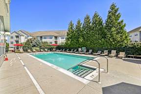 A swimming pool surrounded by lounge chairs and trees.