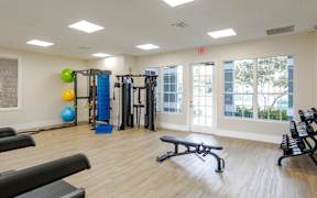 A gym with a variety of equipment including a bench, weights, and a ball.