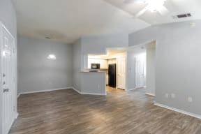 the living room and kitchen of an empty apartment with wood flooring