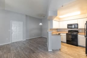 an open kitchen and living room with a wood floor and white cabinets