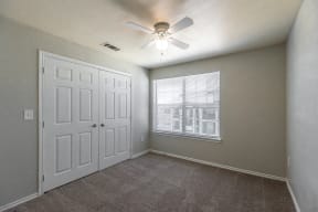 an empty bedroom with a ceiling fan and a window