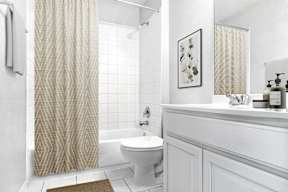 A white bathroom with a toilet, sink, and shower curtain.