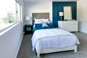A bedroom with a white bed and a blue headboard.