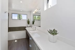 A white bathroom with a large mirror and a white sink.